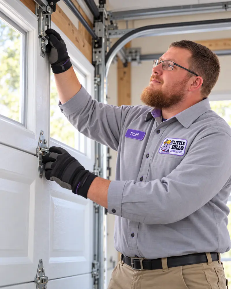 Tyler from Little Dillo Service Co adjusting the hinges on a residential garage door