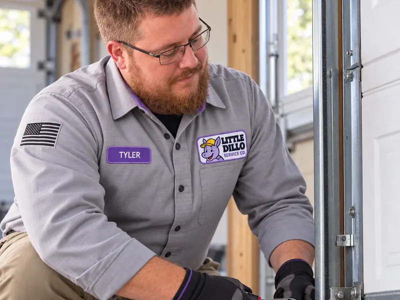 Little Dillo technician tightening garage door track hardware during a door installation