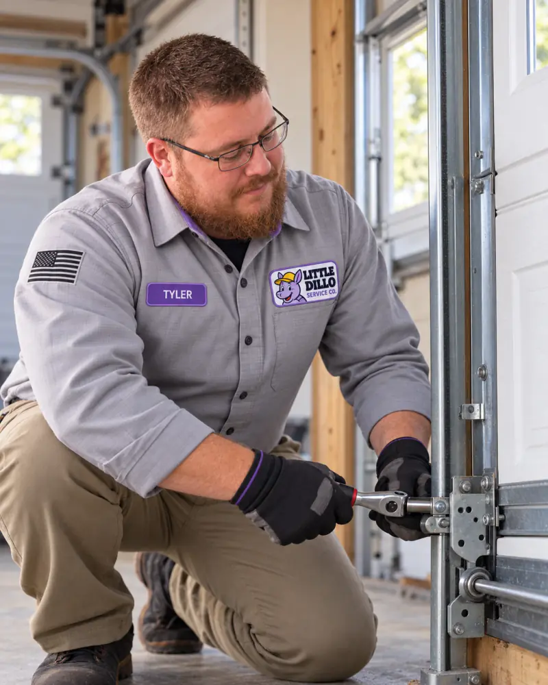 Little Dillo technician tightening garage door track hardware during a door installation