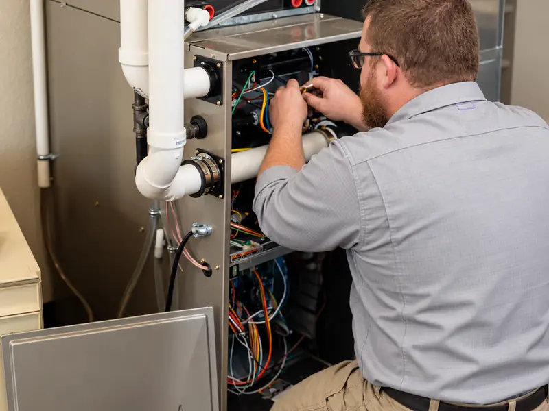 Little Dillo technician checking the wiring inside a high-efficiency gas furnace