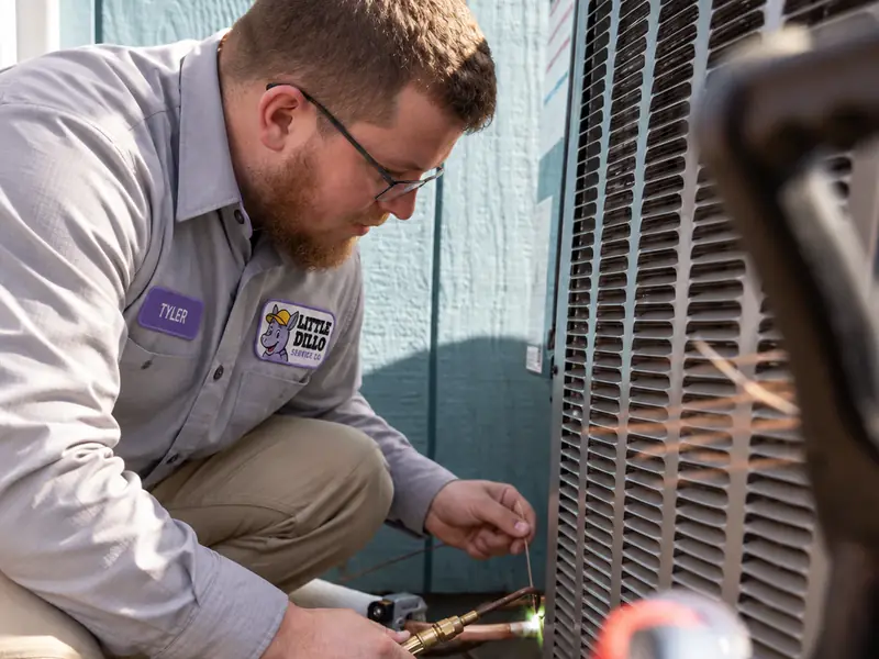 Tyler from Little Dillo brazing the copper line set on an outdoor air conditioner